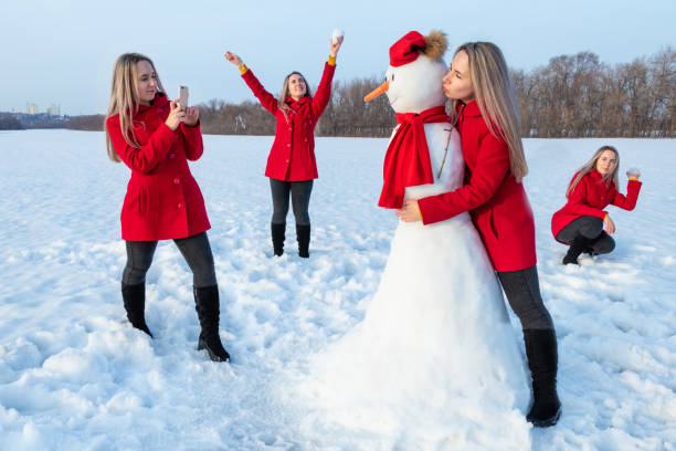 Attractive woman in red coat and her clones taking selfie and playing with snowman in winter Attractive woman in red coat and her clones taking selfie and playing with snowman in winter same person multiple images stock pictures, royalty-free photos & images
