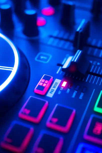 DJ mixing desk turntable in colored wedding disco party lights.