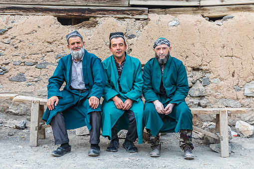 Haft Kul, Sughd Province, Tajikistan. August 17, 2021. Three men in long coats in a mountain village.