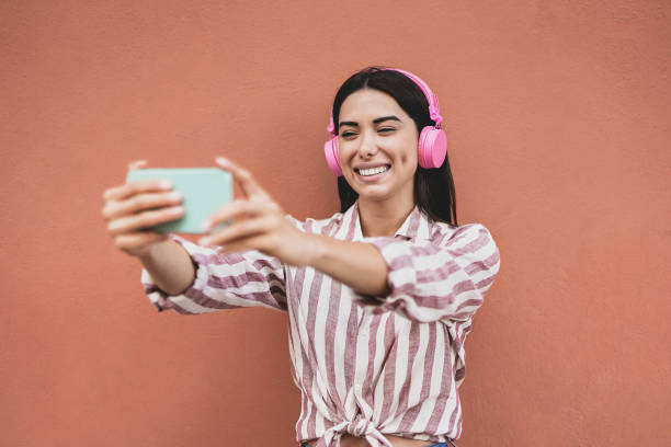 istock Influencer latin girl streaming live video using mobile phone while wearing wireless headphone 1352540387
