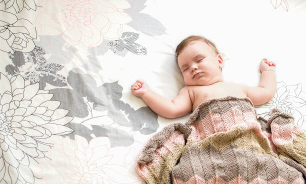 istock A small child sleeps on a large bed under a knitted blanket 1352545758