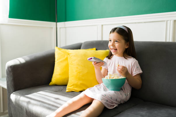 istock Cheerful little girl watching television 1352551123