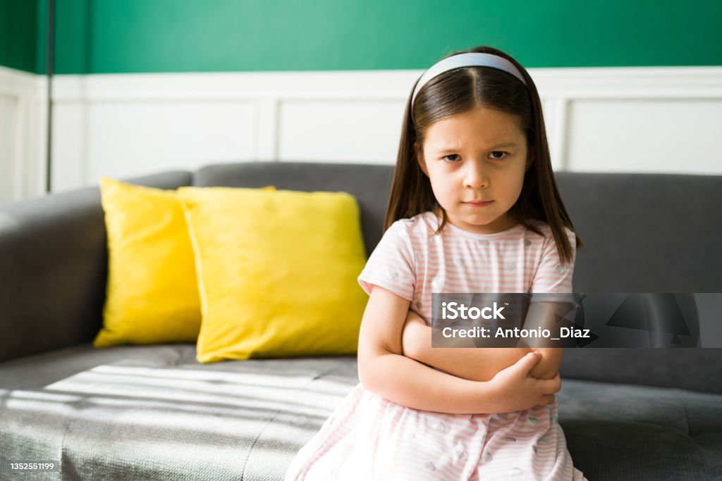 Annoyed girl throwing a tantrum Angry little kid with bad temper feeling annoyed after disobeying her parents. Upset 5 year old girl looking at the camera Brat Stock Photo