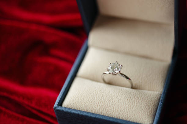 istock Diamond ring in jewelry gift box on red fabric background 1352553598