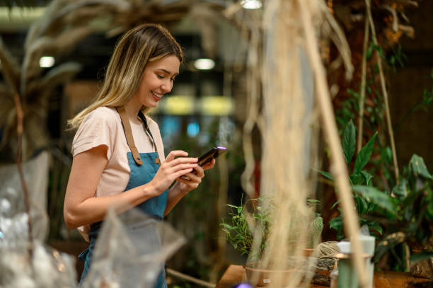istock Florist using smartphone in a flower shop 1352554050