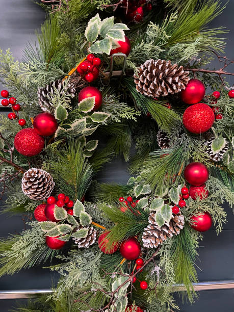 istock Close-up image of Christmas wreath, artificial red berries, pine needles, dried pine cones sprayed with white snow, seasonal decoration, elevated view 1352555821