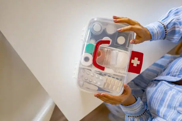 Photo of Closeup female hand placing medicament domestic first aid kit. Storage organization emergency supply