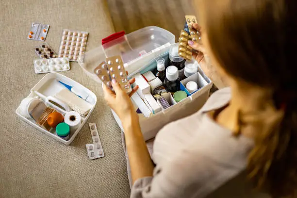 Photo of Closeup female hand placing medicament domestic first aid kit. Storage organization emergency supply