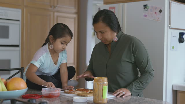 Cute little girl helping her mom make sandwiches for lunch