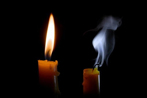 Burning and extinguished candles in the darkness.
