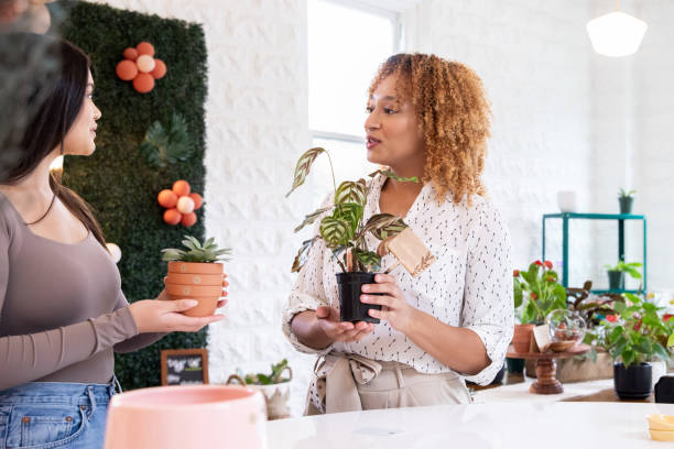 femmes tenant des plantes en pot à l’intérieur d’un magasin - boutique store owner latin american and hispanic ethnicity photos et images de collection