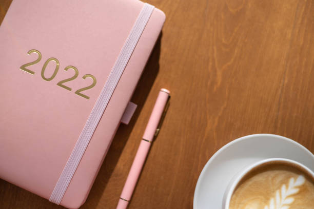istock Pink coral colored diary for the year 2022, pen, coffee 1352576098