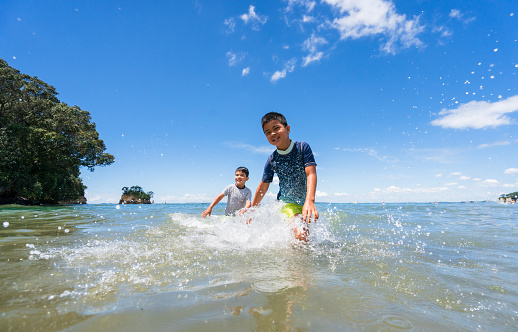 Two small kids enjoying outdoor at sea and playing with water.