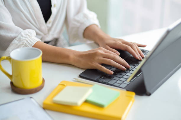 istock Cropped, Businesswoman working, typing on tablet keyboard. 1352583533