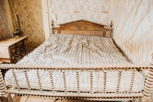 An empty bed  and bed frame sit in an abandoned house in the old gold mining town of Bodie, California.  A reminder of days gone by, the bedroom stands frozen in time.