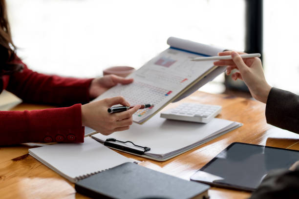 istock Close up view two business woman investment advisors pointing at graph and analyzing financial report in meeting. 1352587610