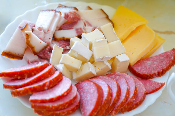 Sausage, bacon and cheese cut into slices on a plate on the dining table