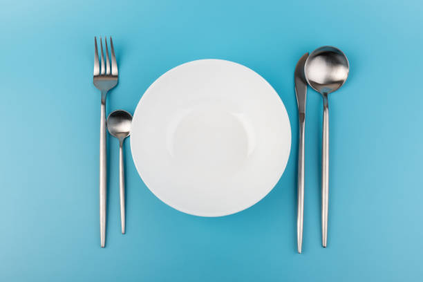istock Empty plate with fork and spoon on blue background. Flat lay Dishes for breakfast, lunch or dinner Mock up 1352591871