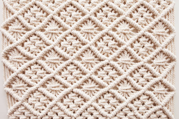 Handmade macrame. Macrame braiding and cotton threads.  Female hobby.  ECO friendly modern knitting DIY natural decoration concept in the interior.  100% cotton wall decoration. stock photo