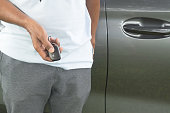 A luxurious car salesman is demonstrating how to use a key remote control to lock, unlock and start car engine, a photo of selective focus with concept of high technological digital key operated car.