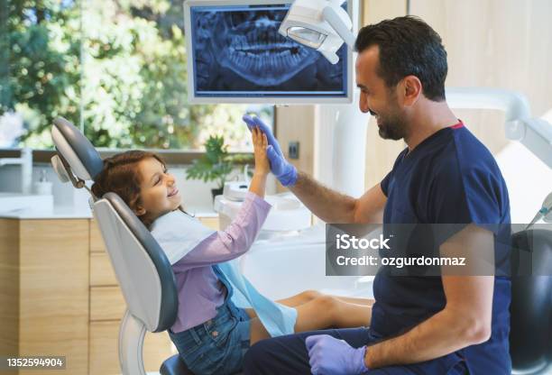 Close Up Portrait Of A Male Dentist Giving A High Five To Little Girl At Dental Clinic Stock Photo - Download Image Now