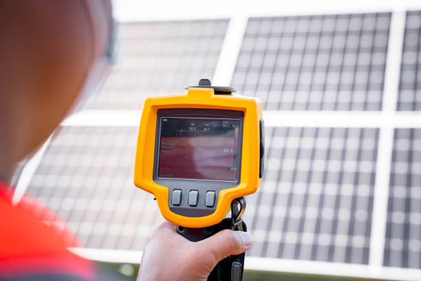 the technician takes the thermoscan(thermal image camera) scan to the solar panel to check the hot spots in the cell, concept to use technology to check the damage in the solar plant - infrared thermometer imagens e fotografias de stock