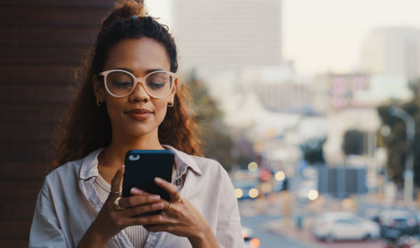 Shot of an attractive young businesswoman texting while standing outside on the office balcony stock photo