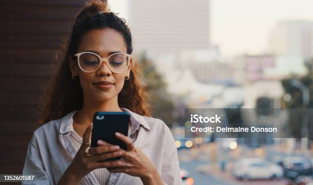 Shot Of An Attractive Young Businesswoman Texting While Standing Outside On The Office Balcony Stock Photo - Download Image Now