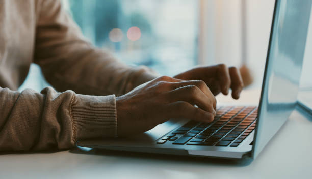 shot of an unrecognizable businessman working on his laptop in the office - internet stockfoto's en -beelden