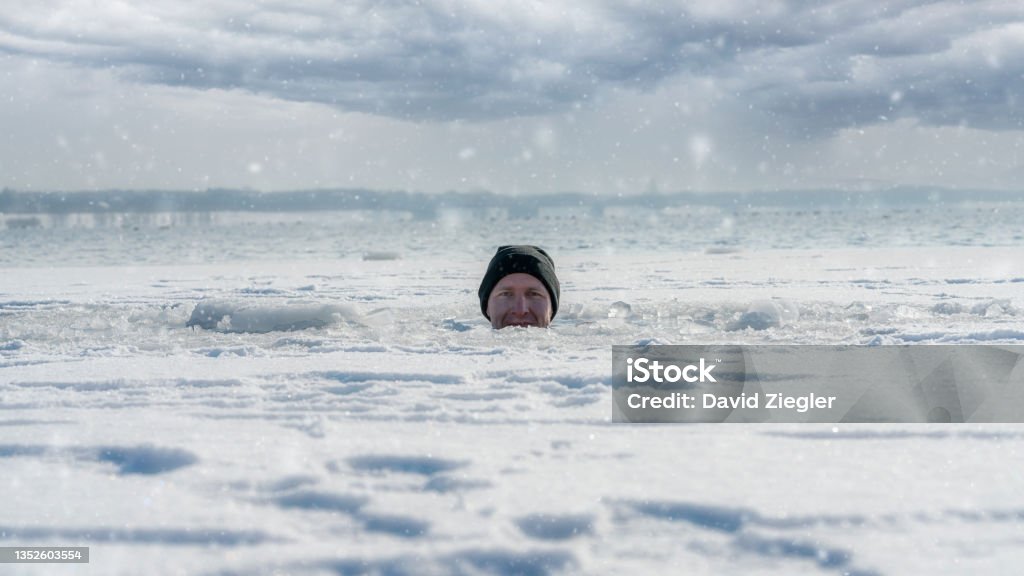 Sitting in a frozen lake A man looking out of an ice hole while having an ice bath in a frozen lake Ice Stock Photo