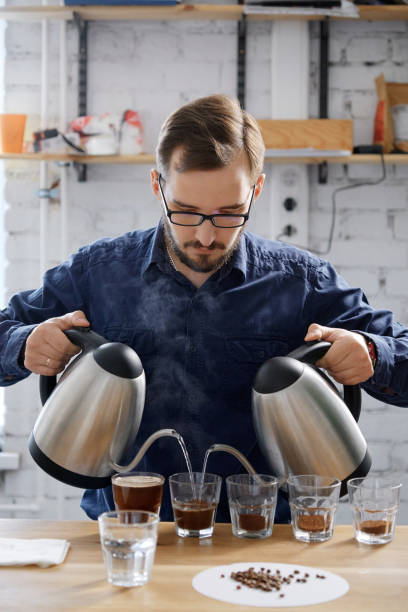 Barista pouring water to coffee cups stock photo