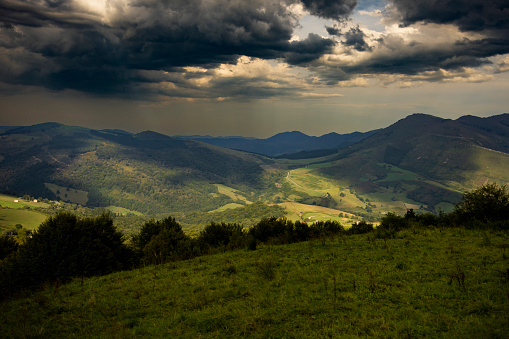 High and wide angle view of dappled light shining on mountains and valley located between Cantabrian range and Pyrenees with dramatic storm clouds overhead.