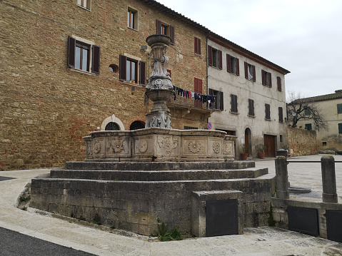 Old fountain in Piazza del grano, a square in Asciano, a town in Siena province, Tuscany.
