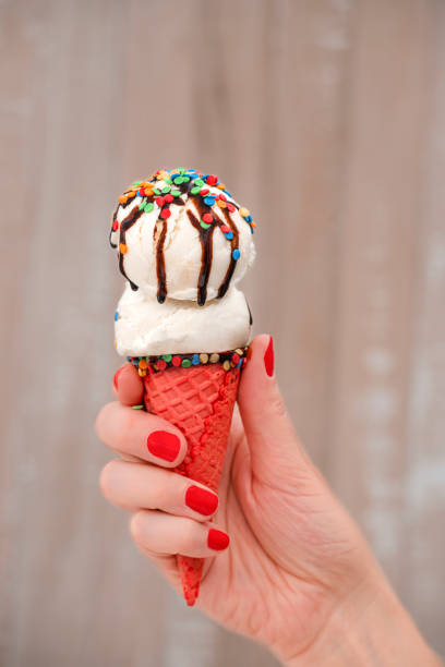 istock Close-up of woman's hand holding vanilla ice cream cone 1352617632