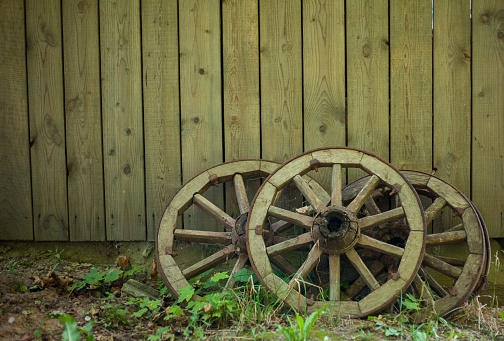 2 old wooden wagon wheels leaning against the wall in an old barn