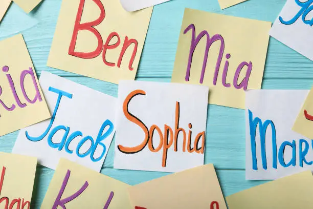 Photo of Paper notes with different baby names on light blue wooden table, flat lay