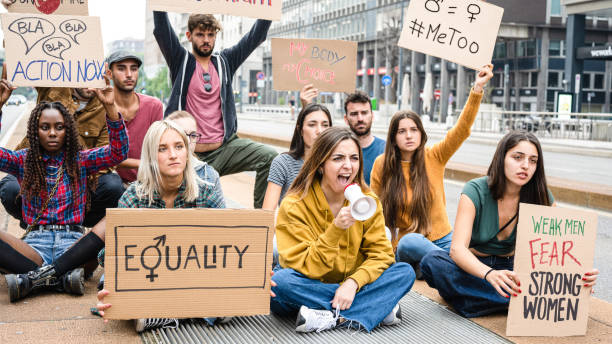 joven feminista con un megáfono en una protesta, grupo de mujeres y hombres multirraciales que apoyan la igualdad de género, #metoo protesta contra la violencia - me too movimiento social fotografías e imágenes de stock