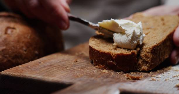 istock Human hands are spreading cream cheese on a slice of bread 1352619163