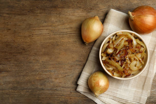 istock Tasty fried onion on wooden table, flat lay. Space for text 1352619190