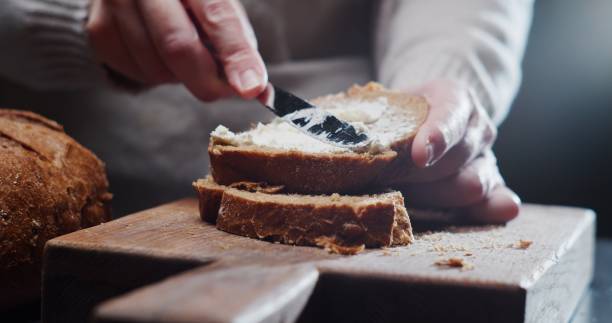 istock Human hands are spreading cream cheese on a slice of bread 1352619273