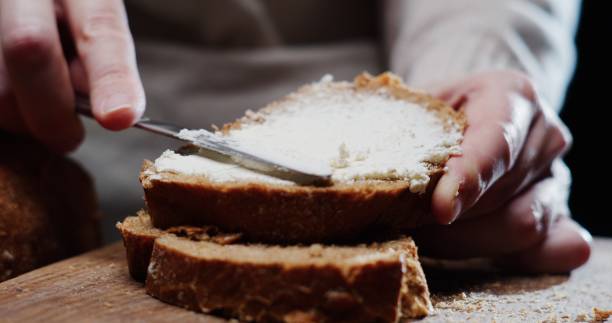 istock Human hands are spreading cream cheese on a slice of bread 1352619280