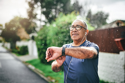 Foto de un hombre mayor parado solo afuera y revisando su reloj después de salir a correr photo