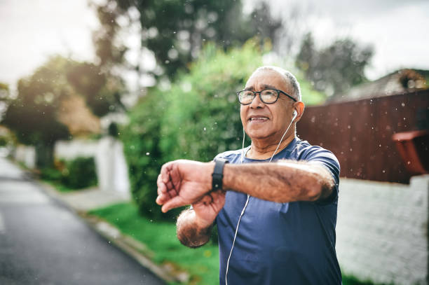 Shot of a senior man standing alone outside and checking his watch after going for a run stock photo