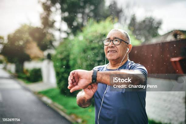Shot Of A Senior Man Standing Alone Outside And Checking His Watch After Going For A Run Stock Photo - Download Image Now