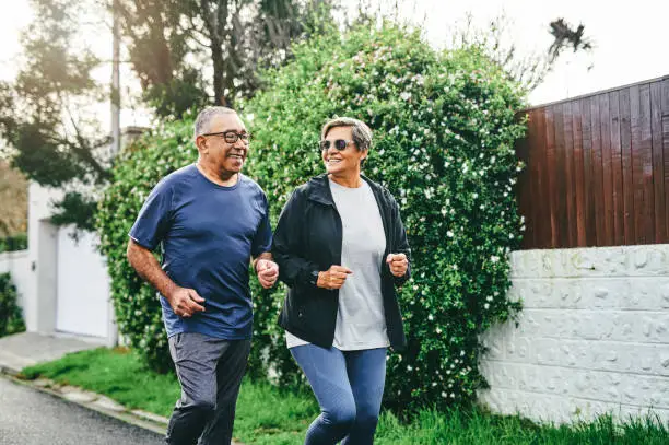 Photo of Shot of a senior couple bonding together while running outdoors