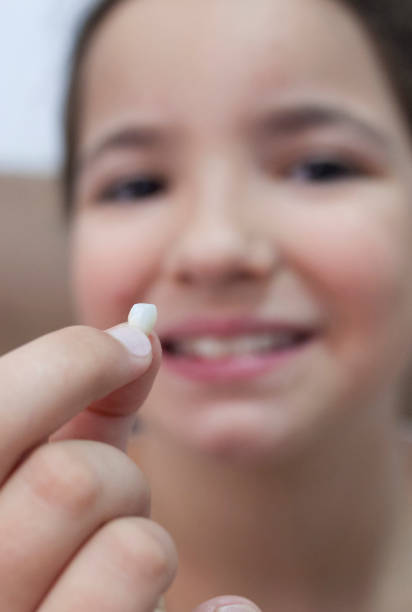 istock 9 years old girl showing her first canine tooth fallen out 1352620732