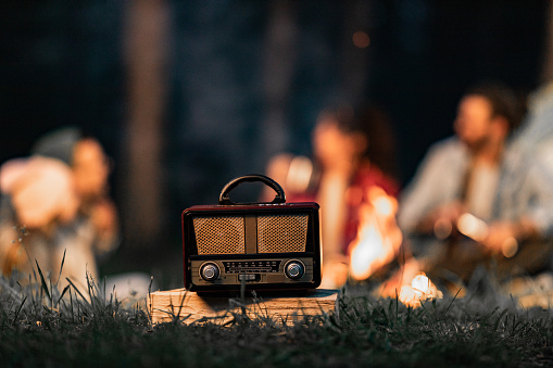 Close up of a vintage radio during camping night with people in the background.