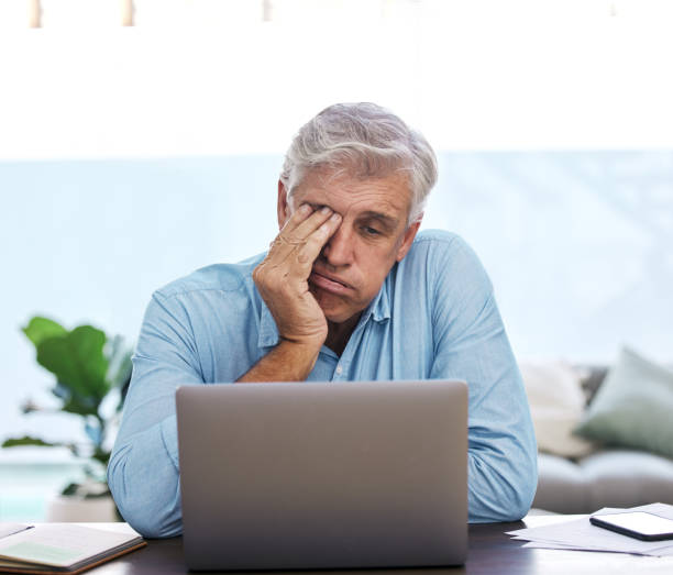 istock Shot of a mature man sitting alone and feeling stressed while using his laptop to work from home 1352622869