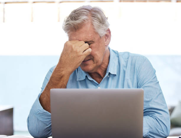 istock Shot of a mature man sitting alone and feeling stressed while using his laptop to work from home 1352622880