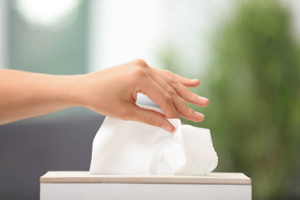istock Woman taking paper tissue from holder on blurred background, closeup 1352623552